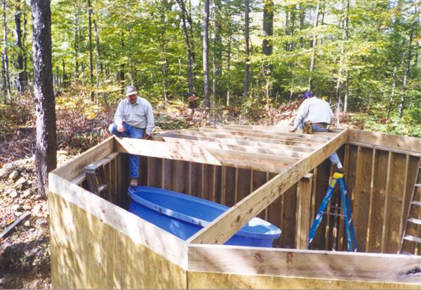 People building a small cabin in the middle of a forest.