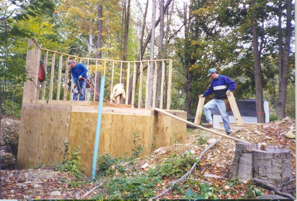 People building a small cabin in the middle of a forest.