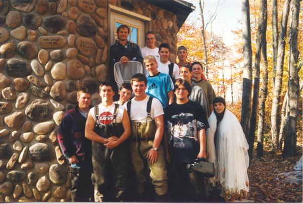 People posing for a picture in front of a small cabin.