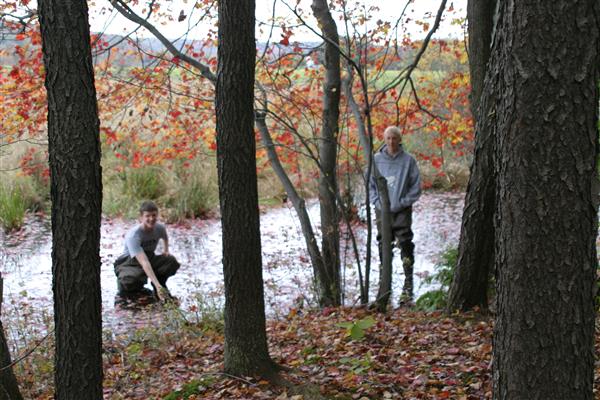 Two guys posing for a picture in the middle of a forest.