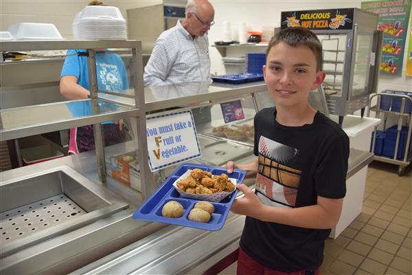 A boy holding a tray with his meal