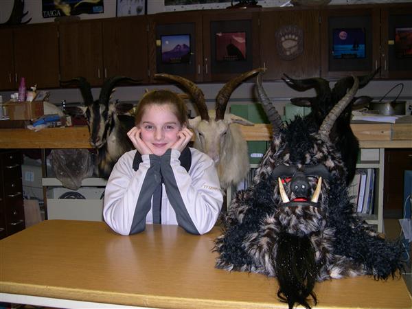 A girl with taxidermied goat surrounding her.