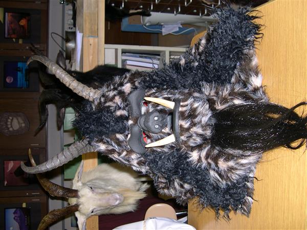 A close-up photo of a furry mask with horns and teeth. The mask is resting on a wooden table.