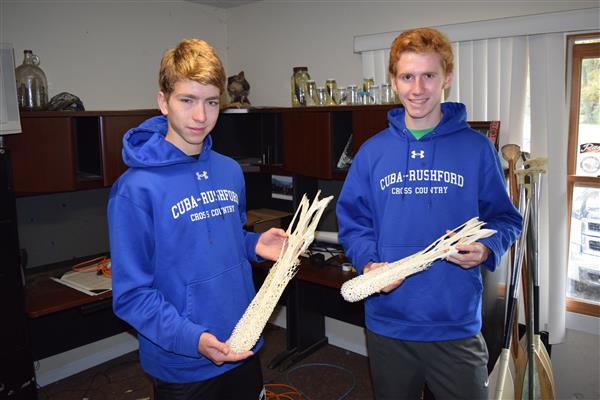 Two boys wearing a blue sweater while holding that seems to be an animal skeleton.