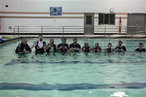 SCUBA Students posing for a picture in the pool with their equipment.