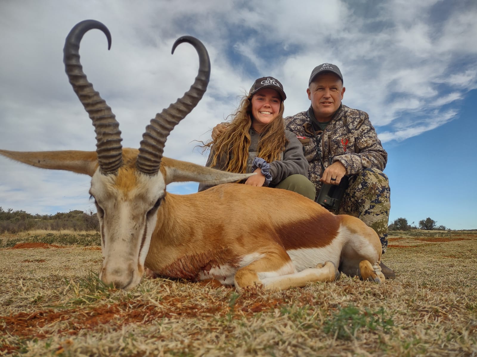 A girl and guy posing with a Springbok they hunted.