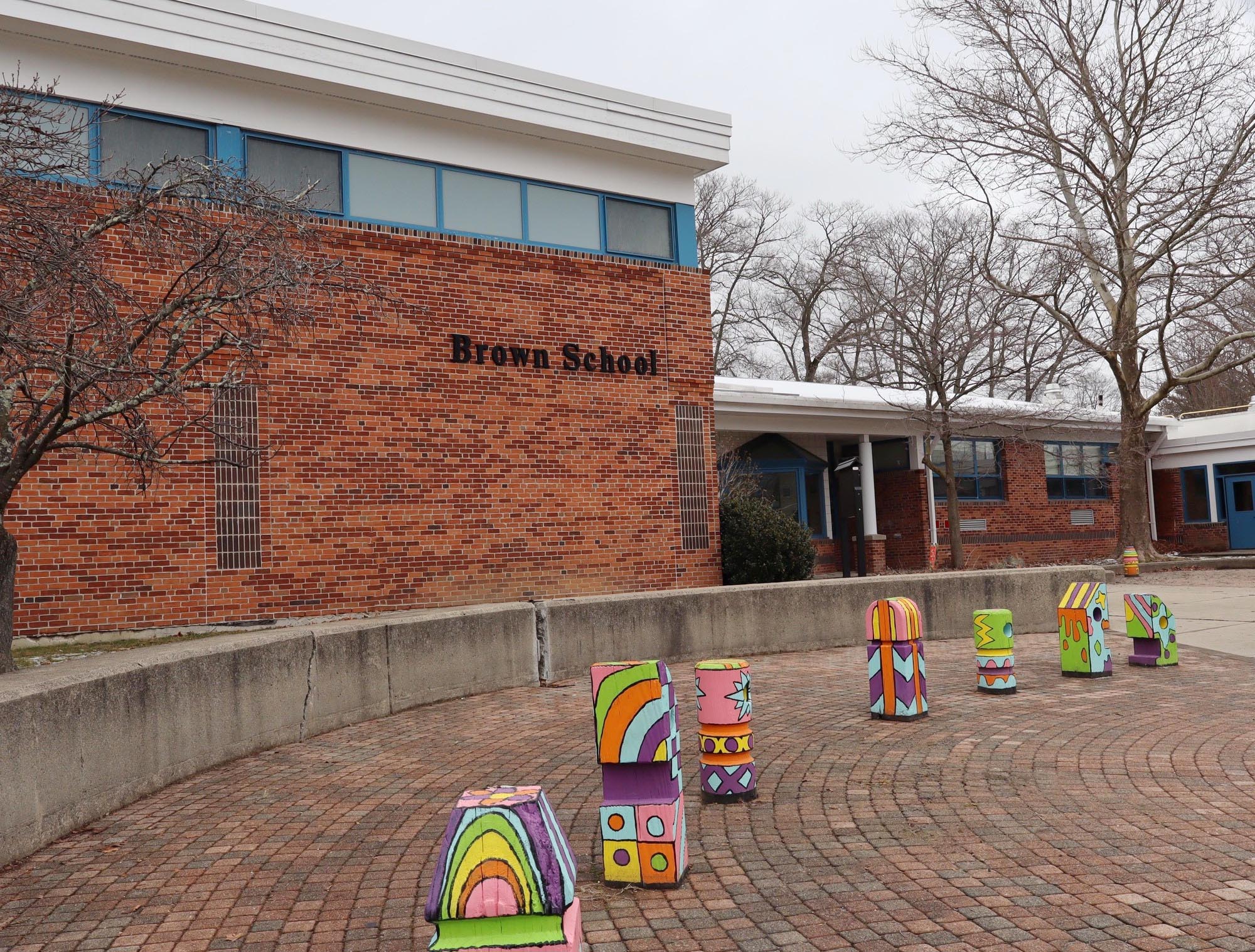 Image of Brown School. Has a red brick exterior and colorful balastrades that are painted in all colors of the rainbow out front.  The building was erected in 1950.