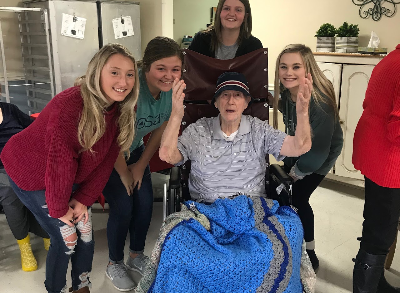Students with an elderly person in a wheelchair posing for photo