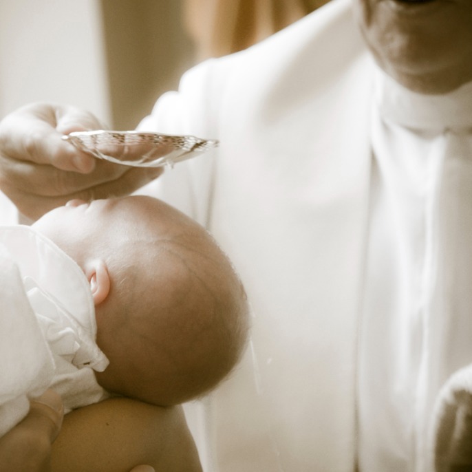 An image of a priest gently holding a baby, showcasing tenderness and compassion.