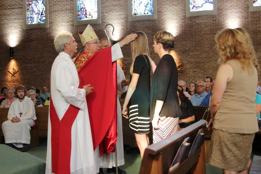 An image of a priest showing kindness by touching a woman's head in a gesture of support.