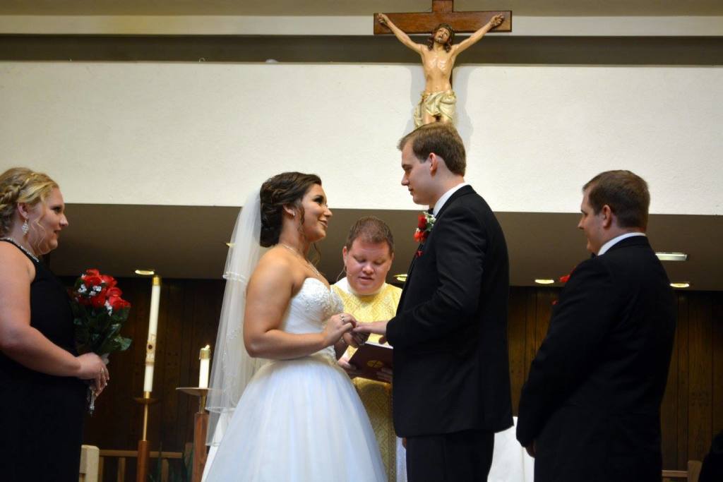 Wedding ceremony with a bride and groom standing in front of a crucifix as they exchange vows.