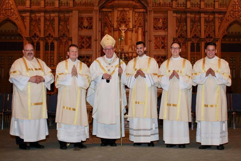 Portrait of the new Archbishop of the Archdiocese of New York, standing in front of a cathedral.