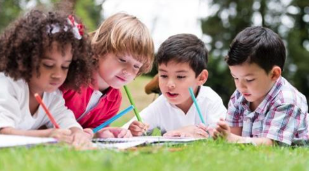 students writing and laying on the grass