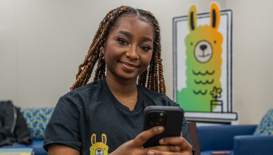 student holding cell phone with Alongside banner