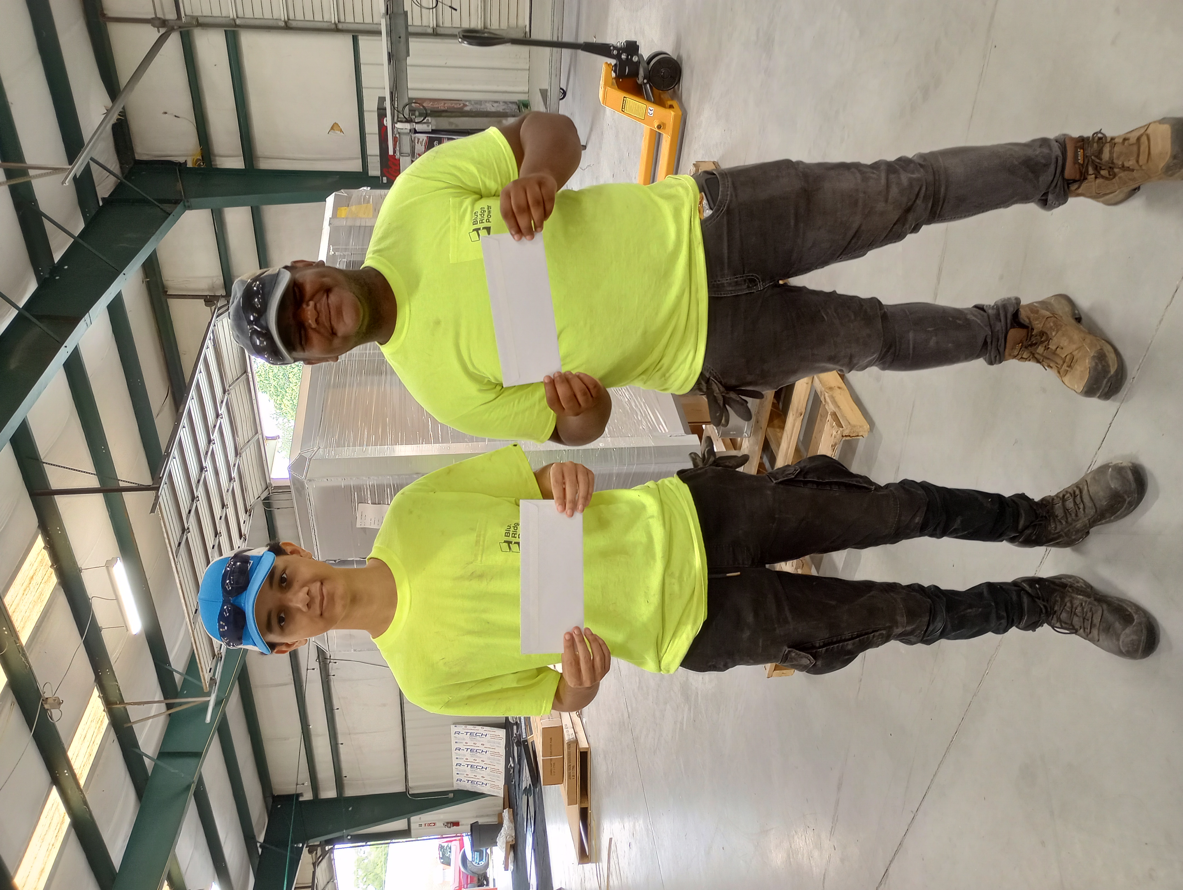 Two students posing in a photo holding their paychecks from the Summer internship program. 