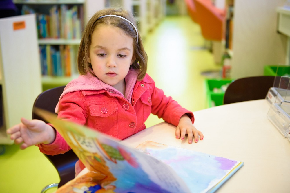 pre-k student reading a book