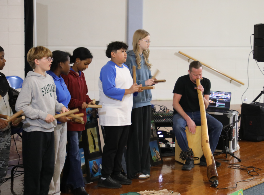 Students playing sticks with performer