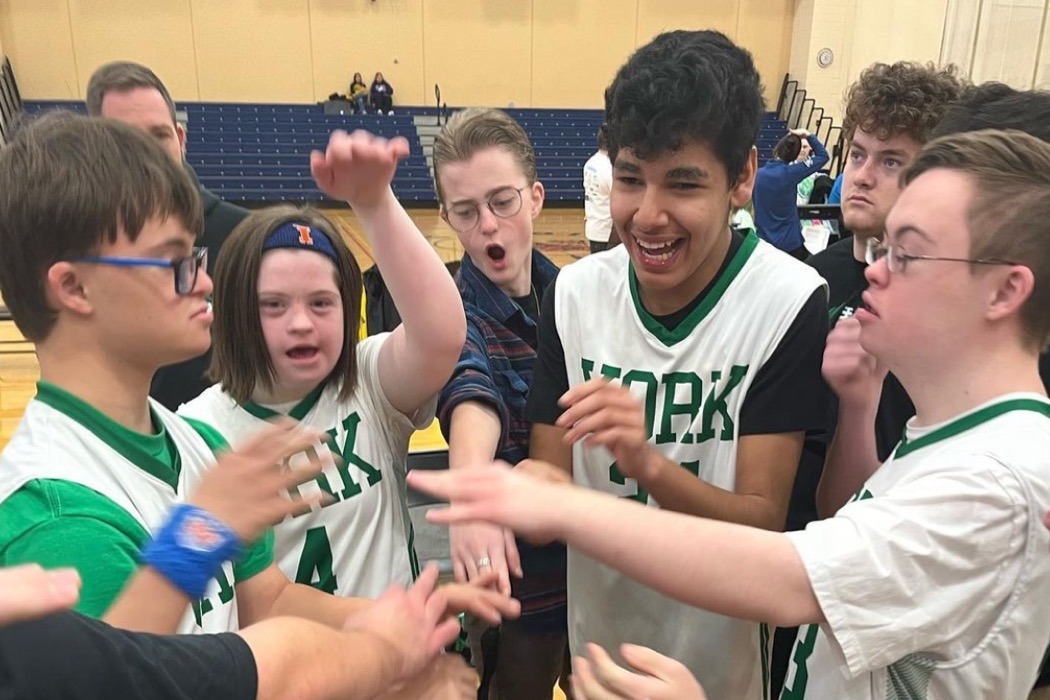 Athletes doing a cheer with their hands in together in the middle