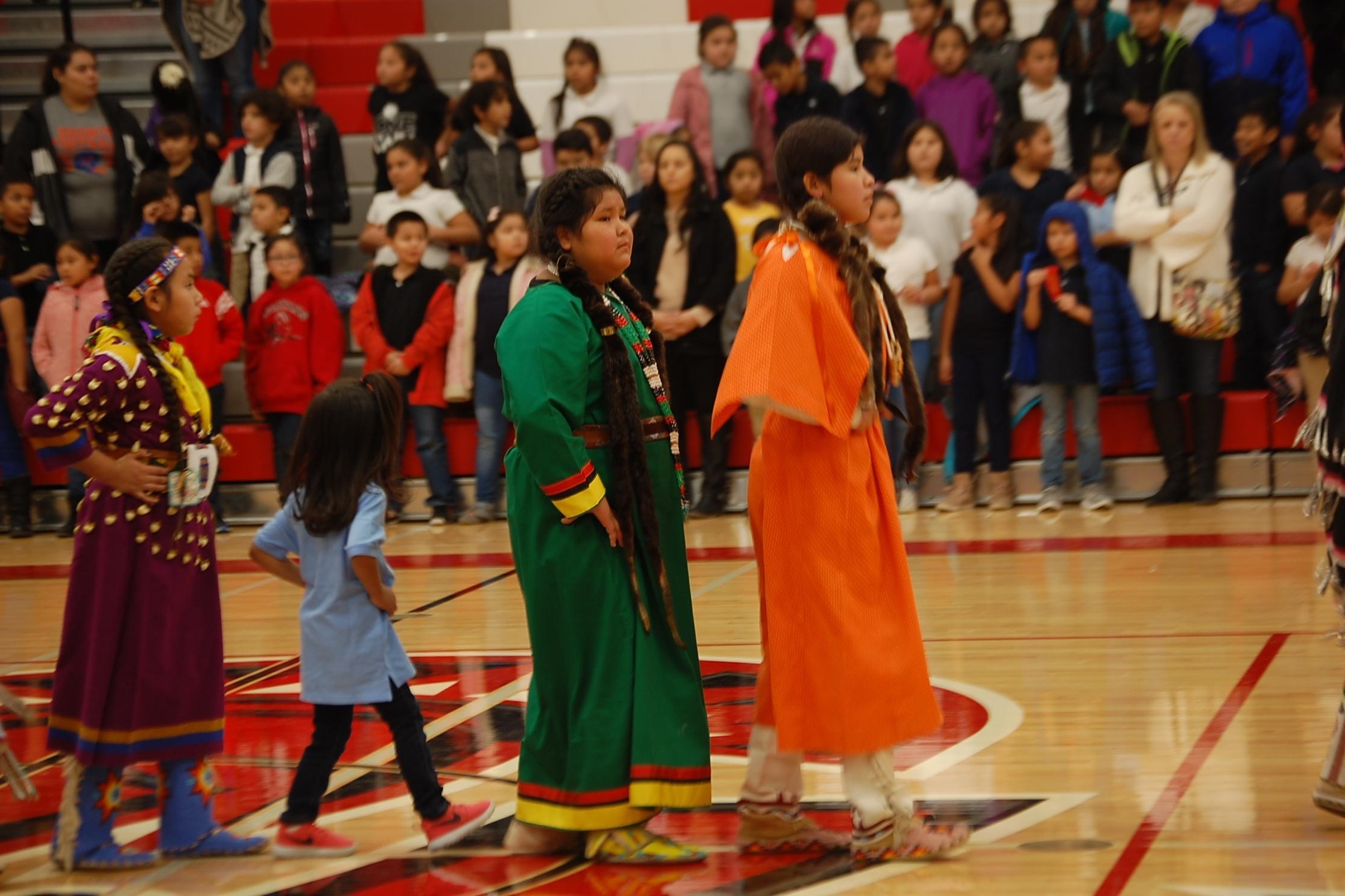 students wearing tribal clothes stand in a gym