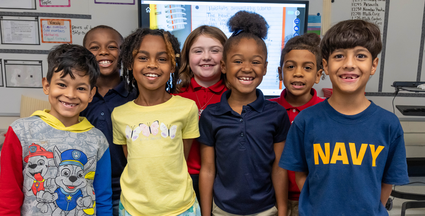 group of students in front of the white board smiling 