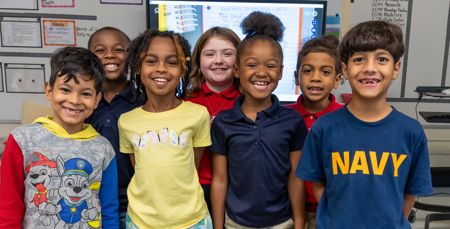 Students smiling at the camera in their classroom