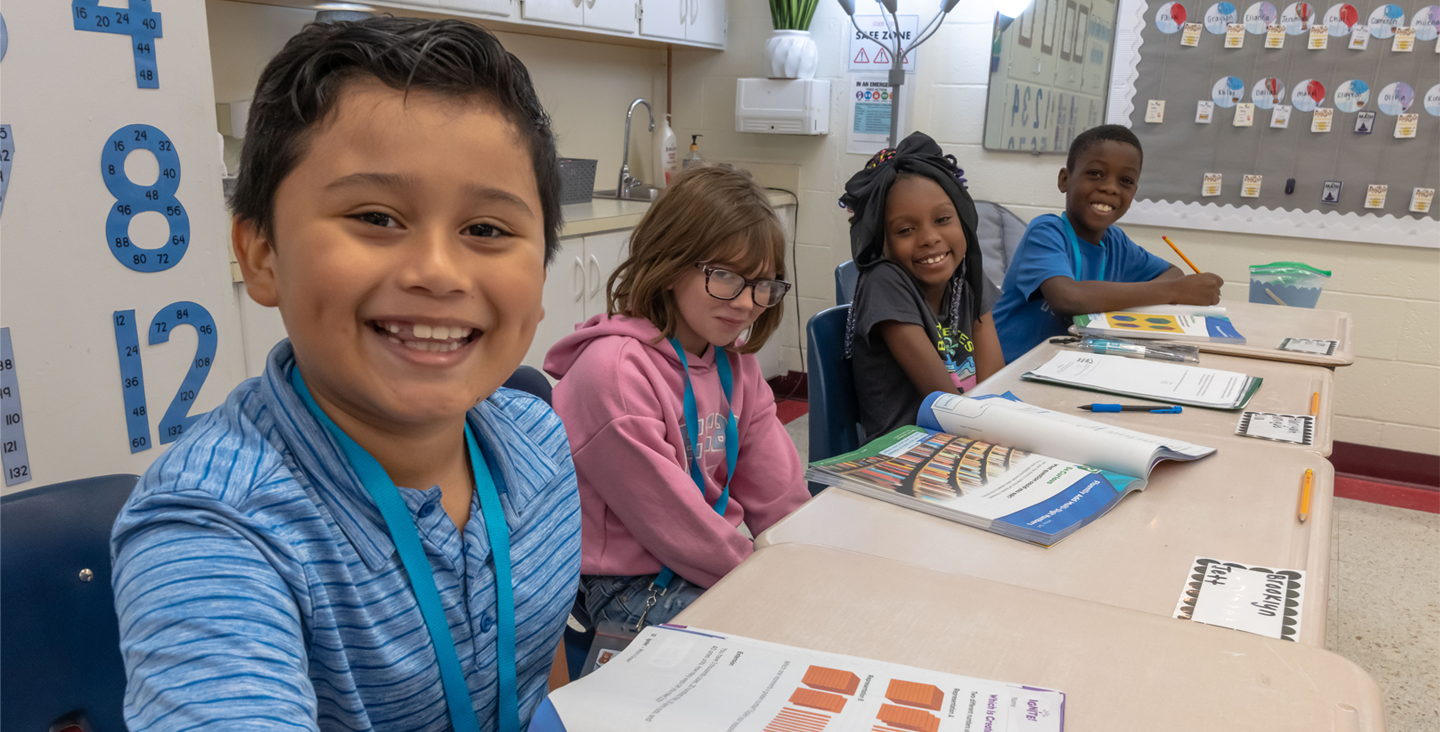 4 students smiling while working in their math books