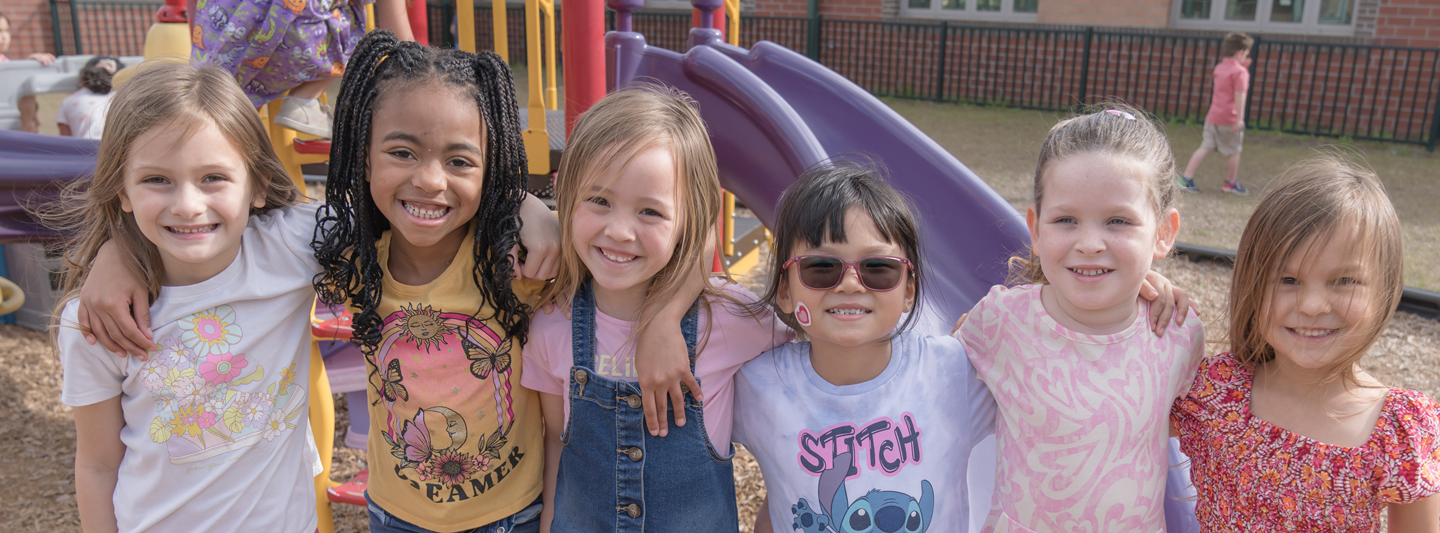 group of girls on a playground standing arm in arm