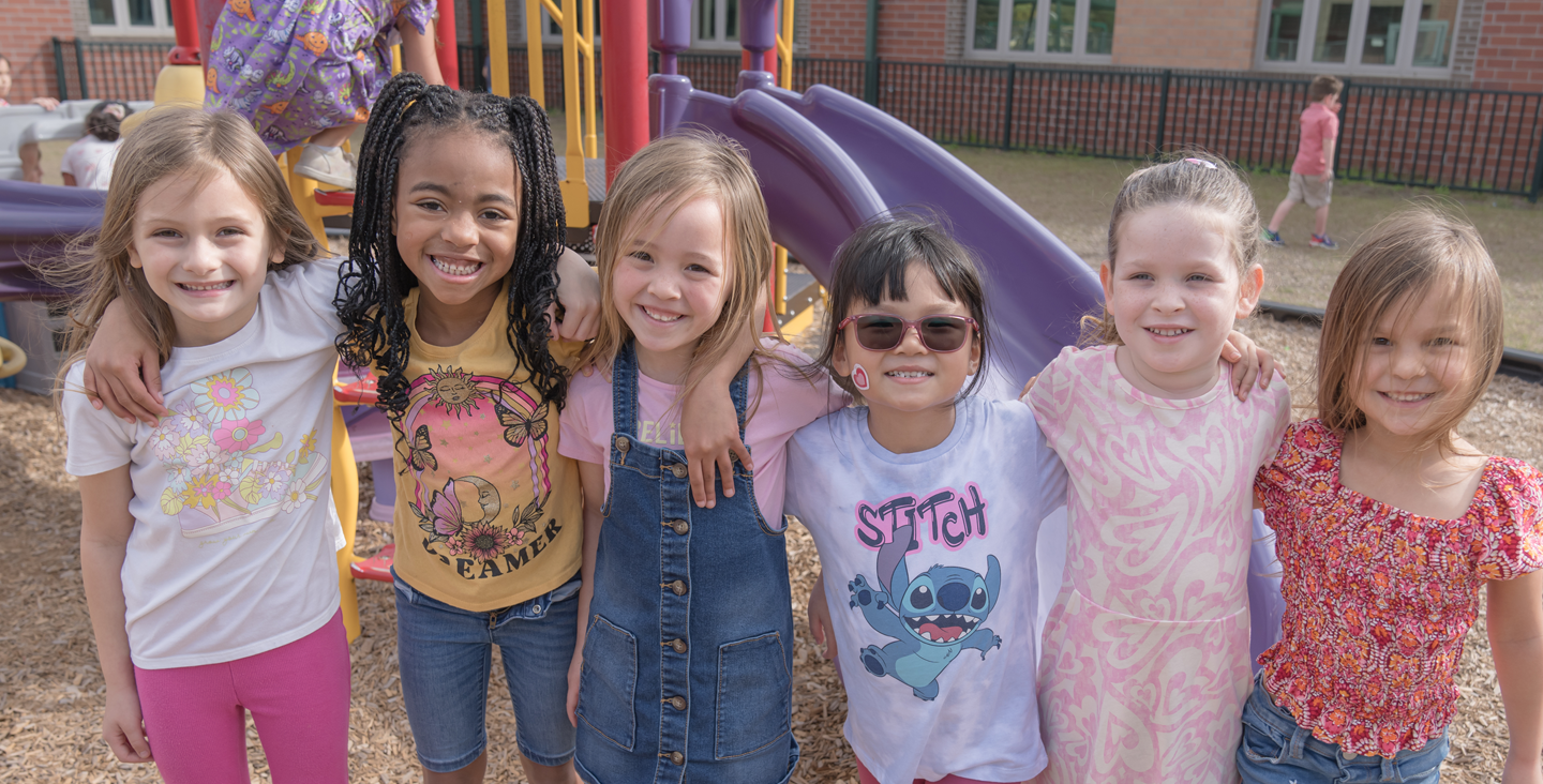 Students on the playground smiling at the camera