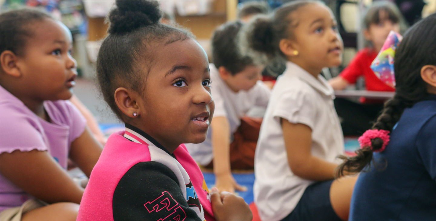 students sitting on the floor listening to their teacher