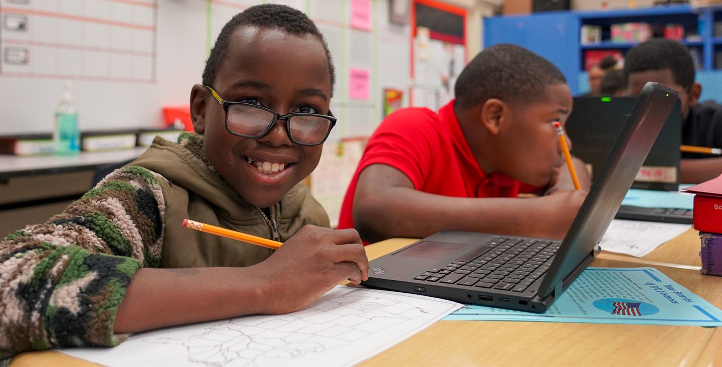 smiling student working on a map of the United States with a laptop