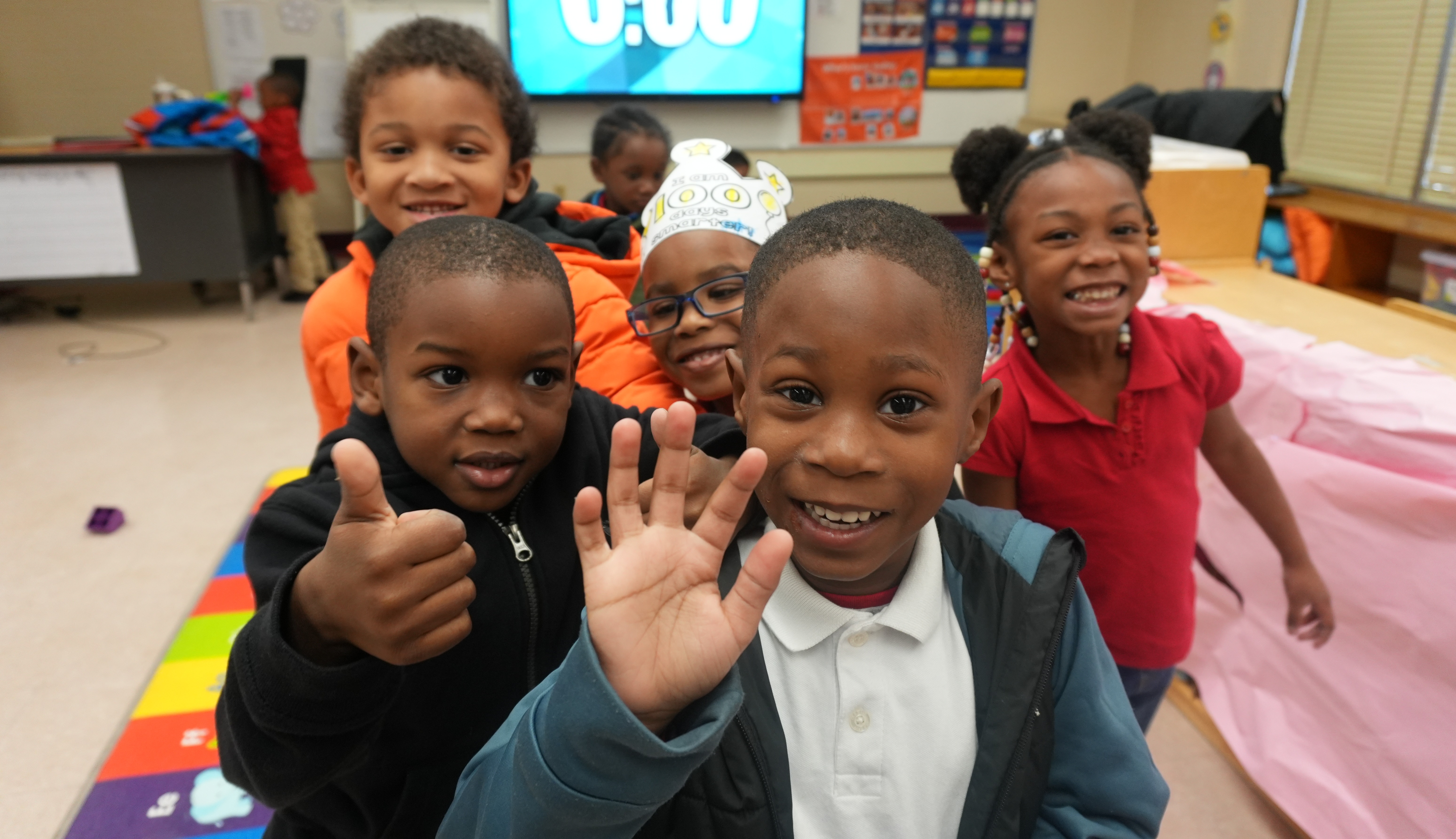 smiling students, waving and giving a thumbs up 
