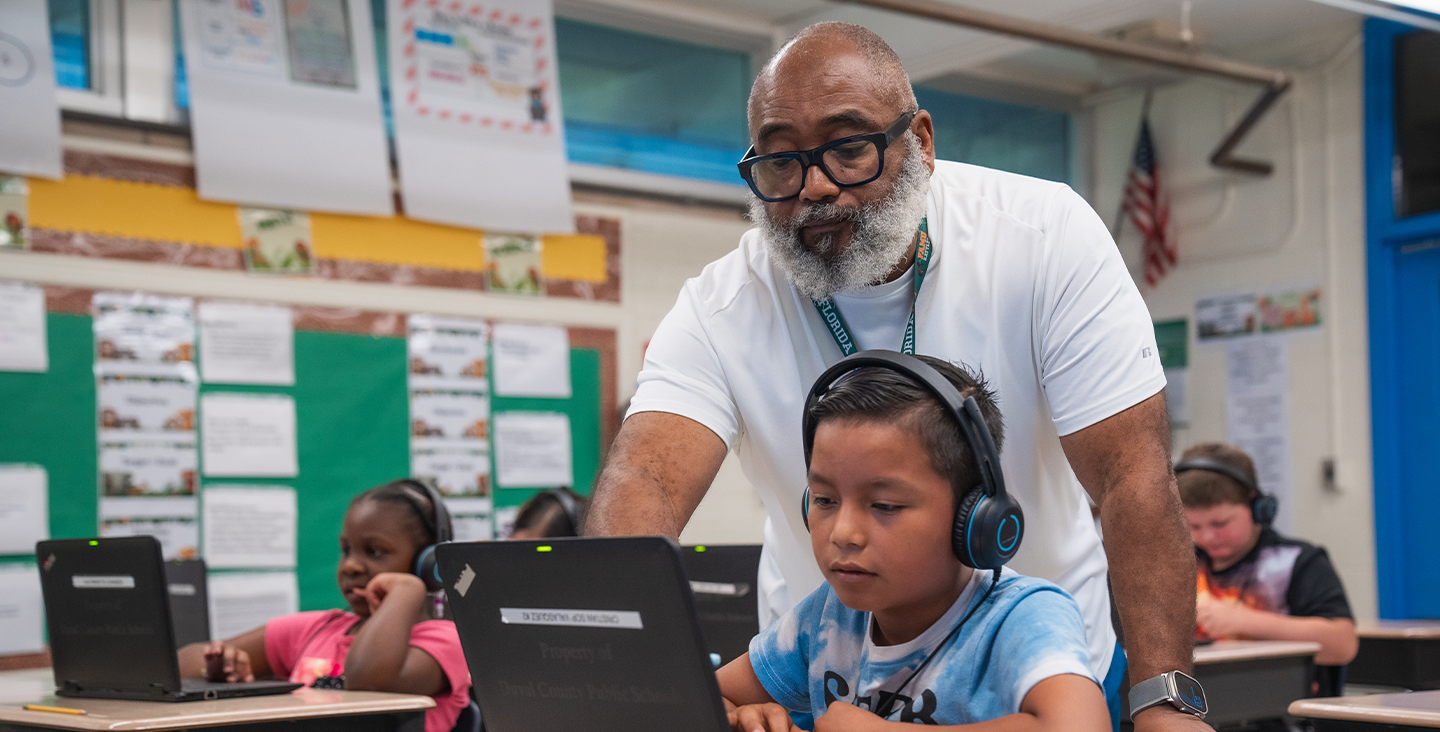 A teacher helping a student on his laptop