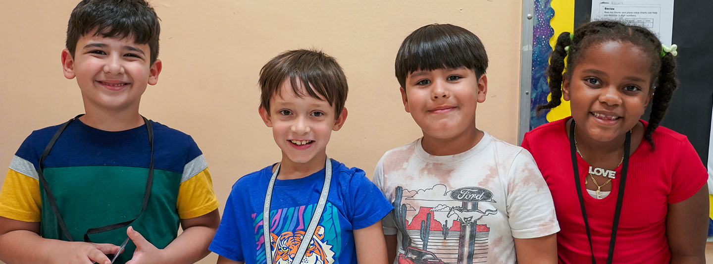 four students smiling at the camera