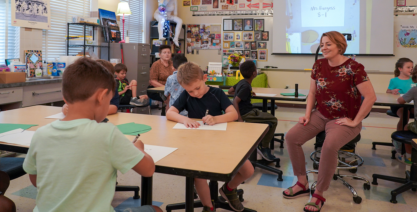 teacher supervising students while they color at a table