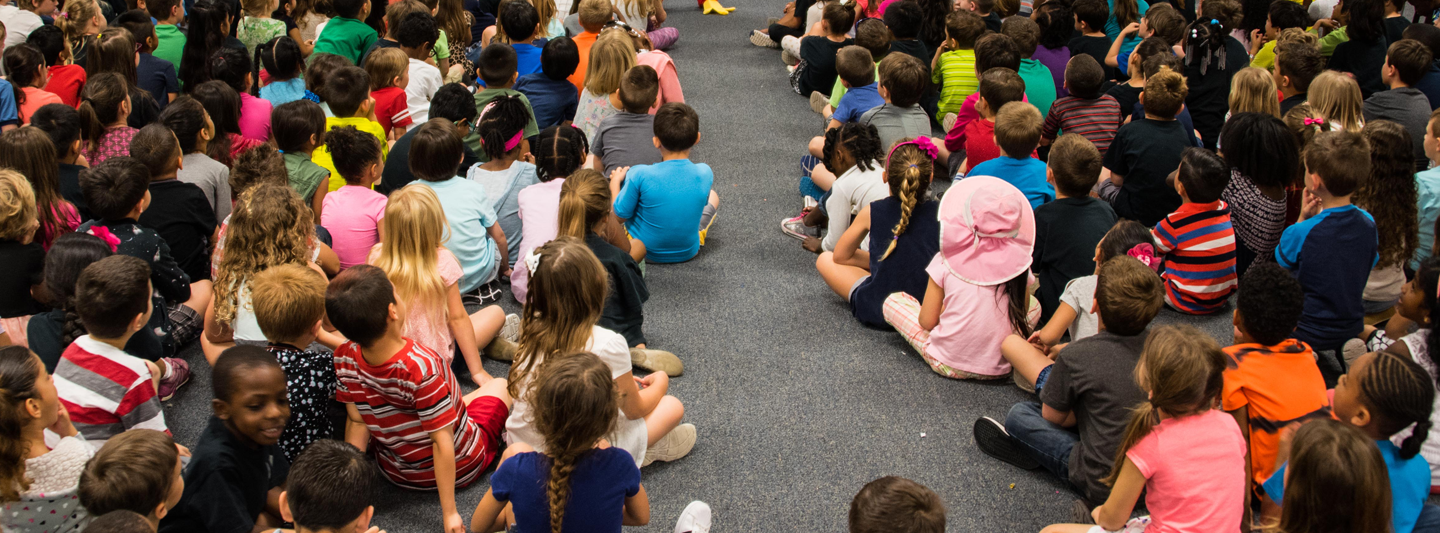 students sitting on the floor at an assembly