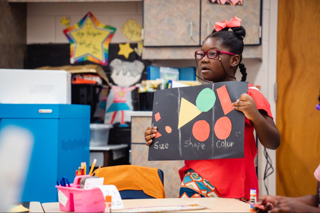 Student standing up and showing off her work
