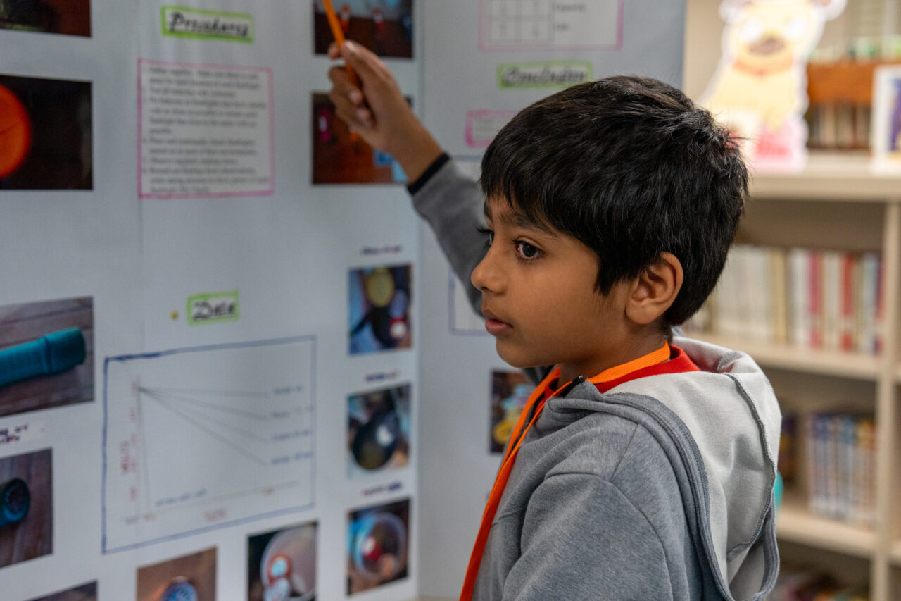 A boy pointing at his science fair board