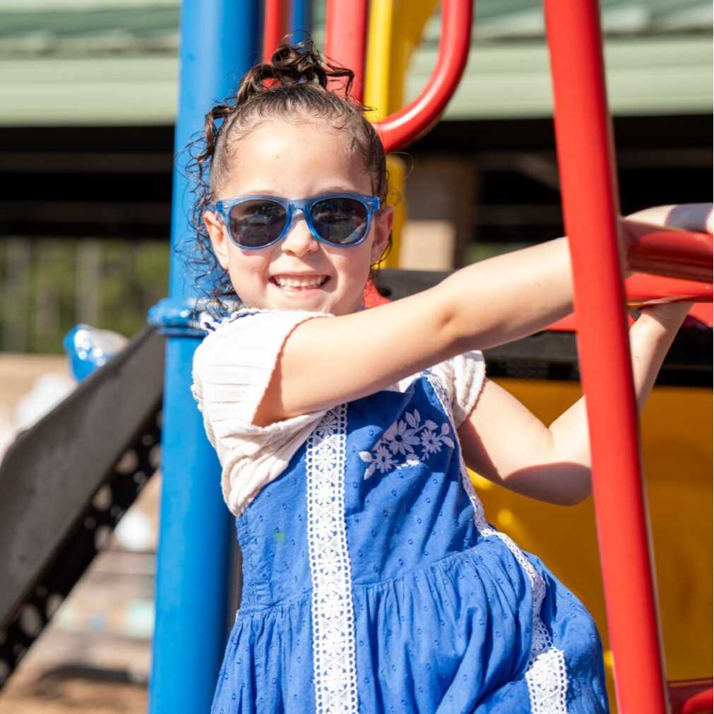Student smiling on the playground with sunglasses on 