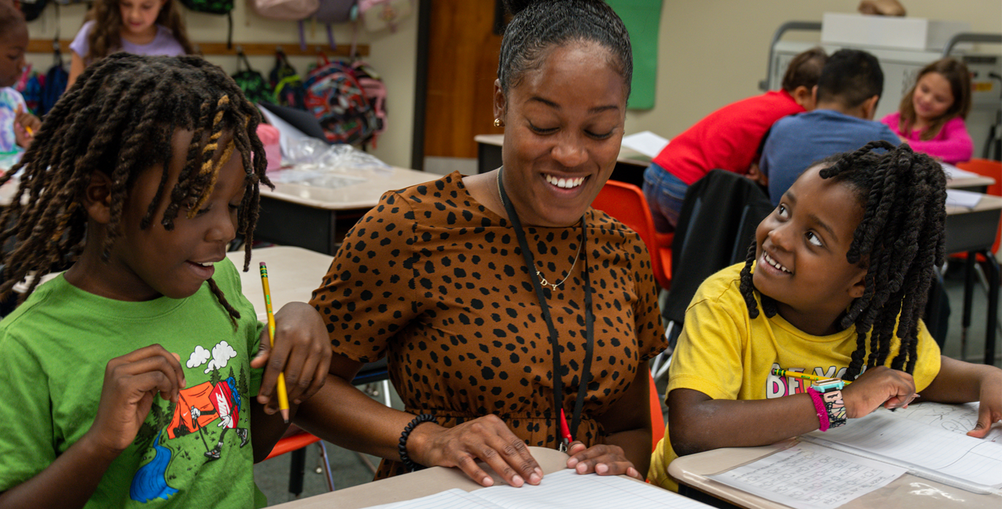 A teacher working with two students 