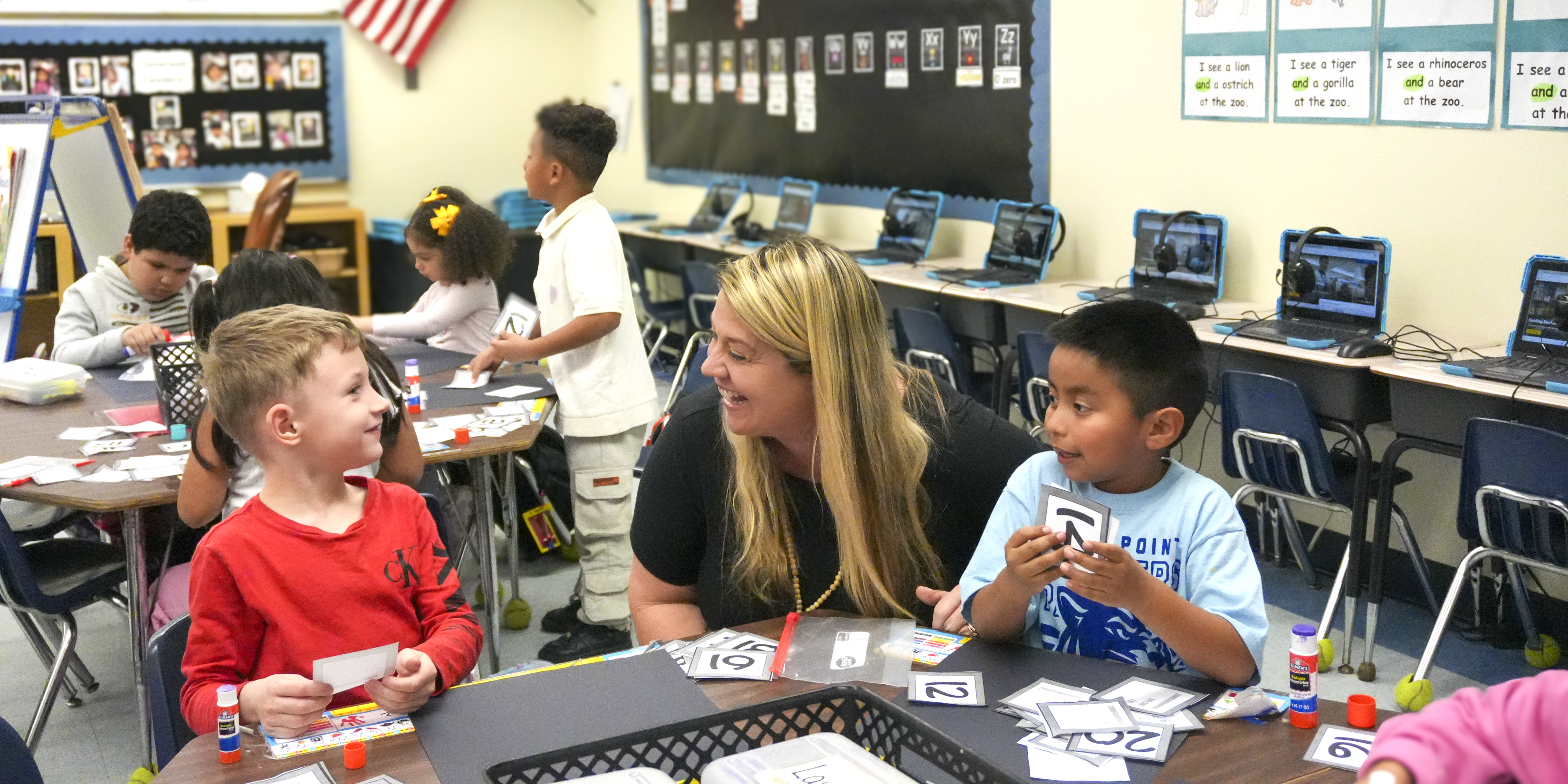 Two smiling young students and a smiling teacher during math class.