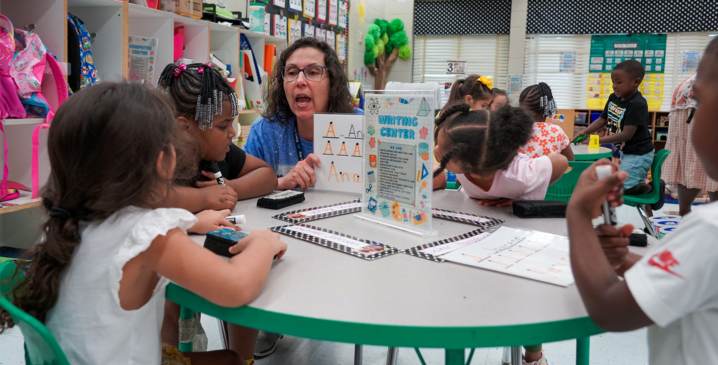 A teacher working with students in a small group writing center