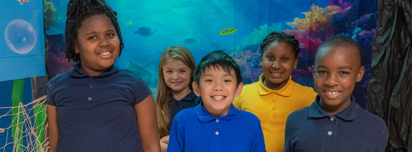 students posing in front of aquarium artwork