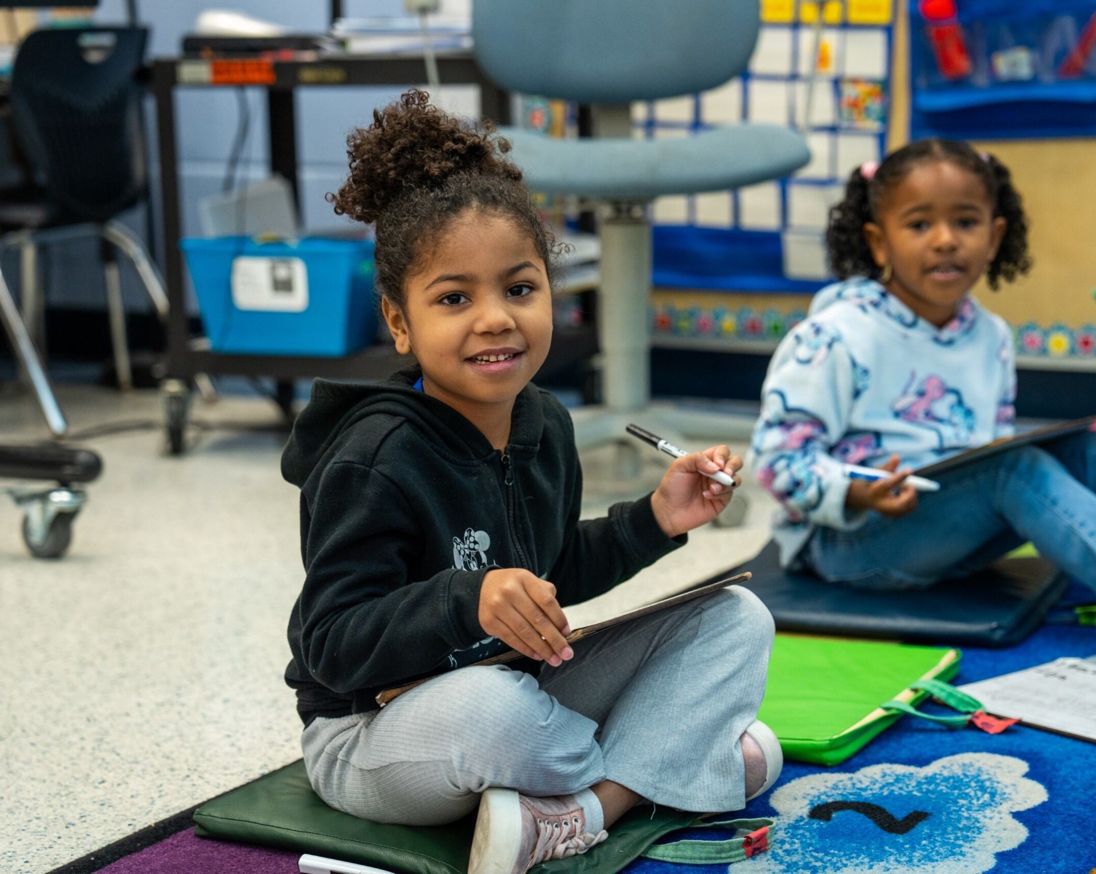 A girl smiling with a white board and marker