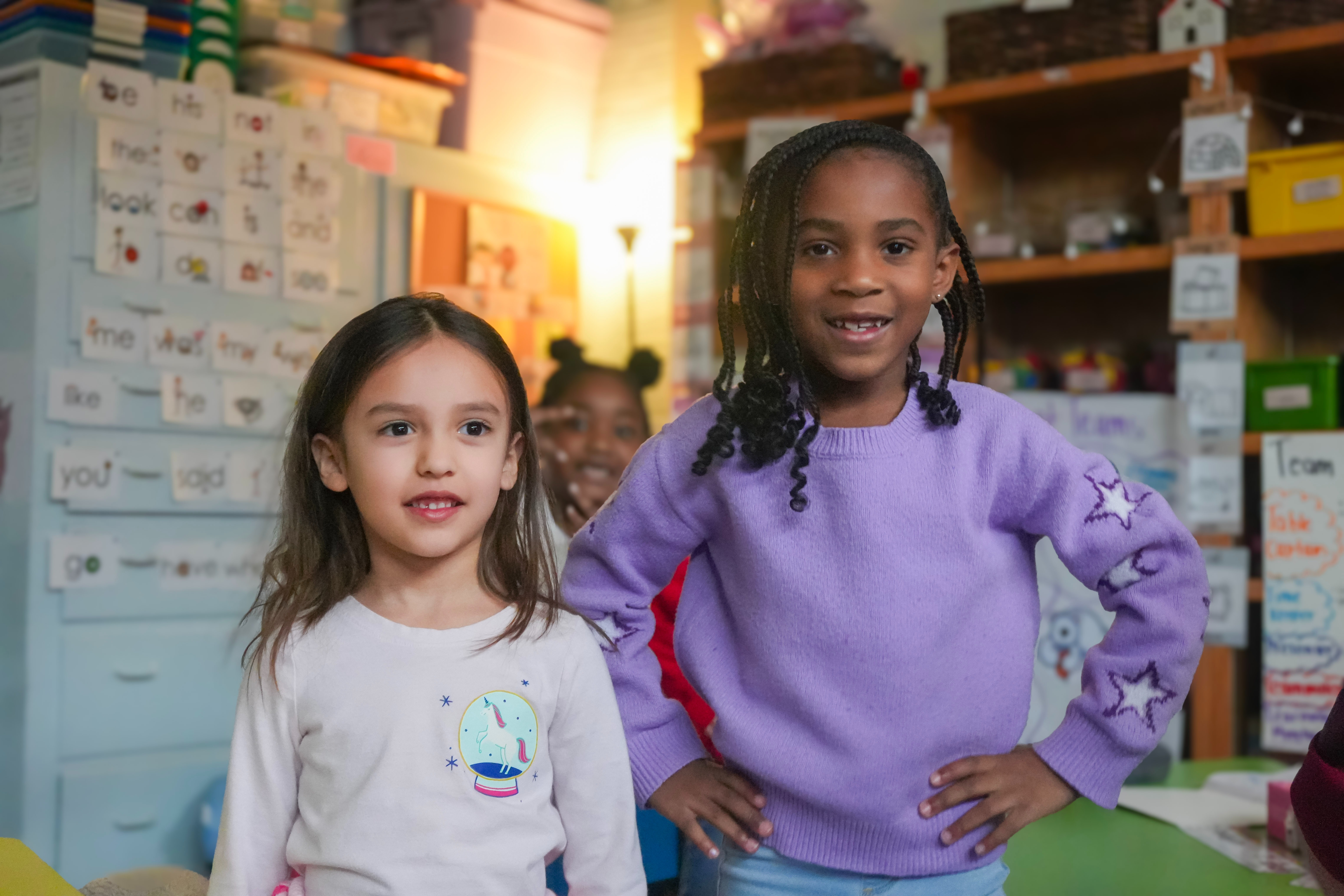 Two students smiling next to each other, student on the right has her hands on her hips