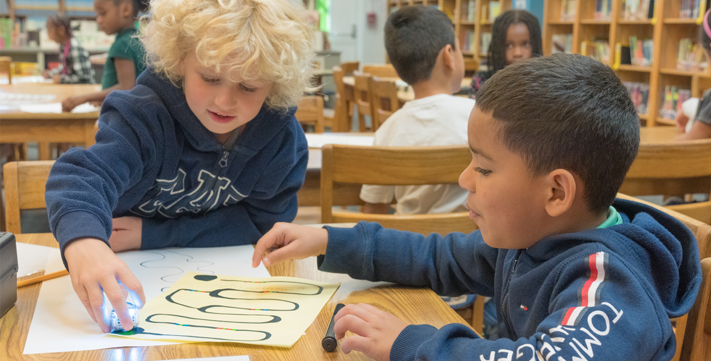 two students working on a drawing in the library