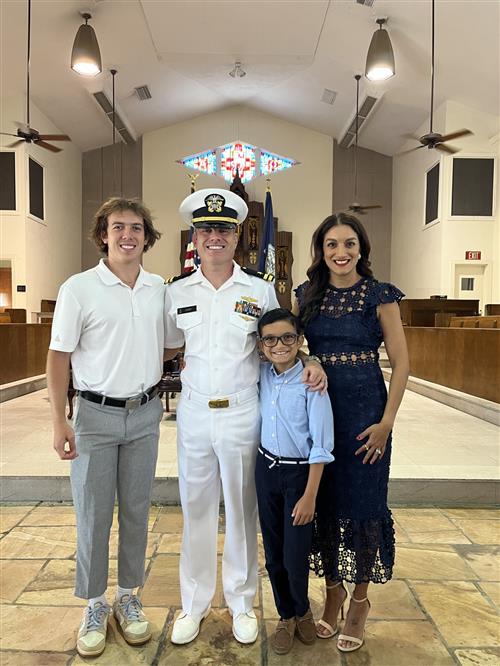 A family standing together. The dad is wearing a military uniform. There is also a mom and two sons.