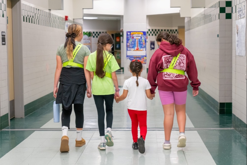Safety Patrols walking a younger student down the hall.