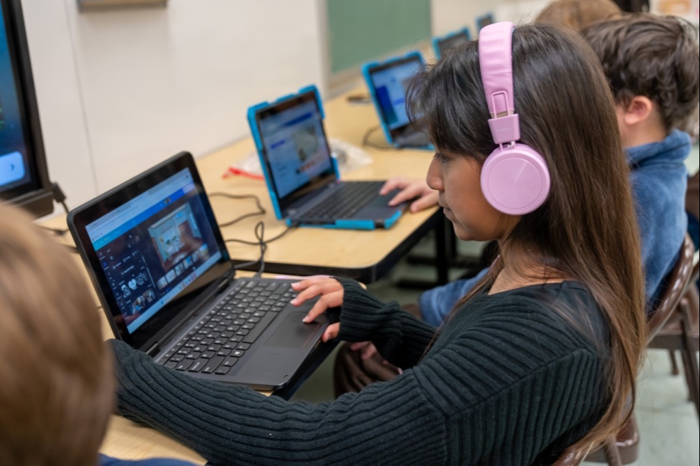 Students working on graphic design projects on laptops.