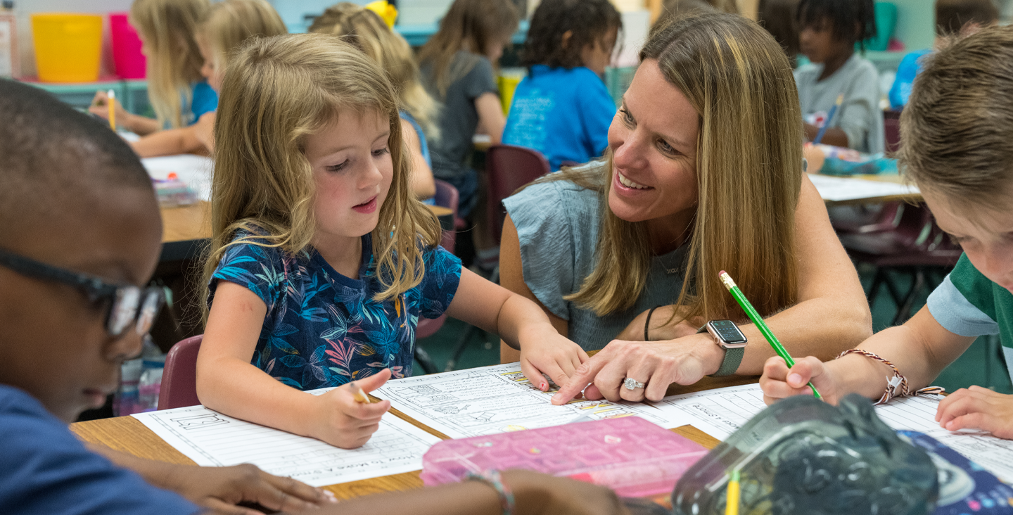 teacher sitting next to student in class