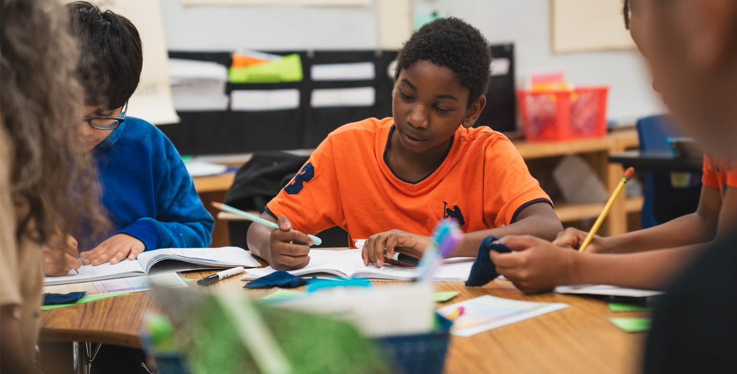 Students at a table writing in their notebooks